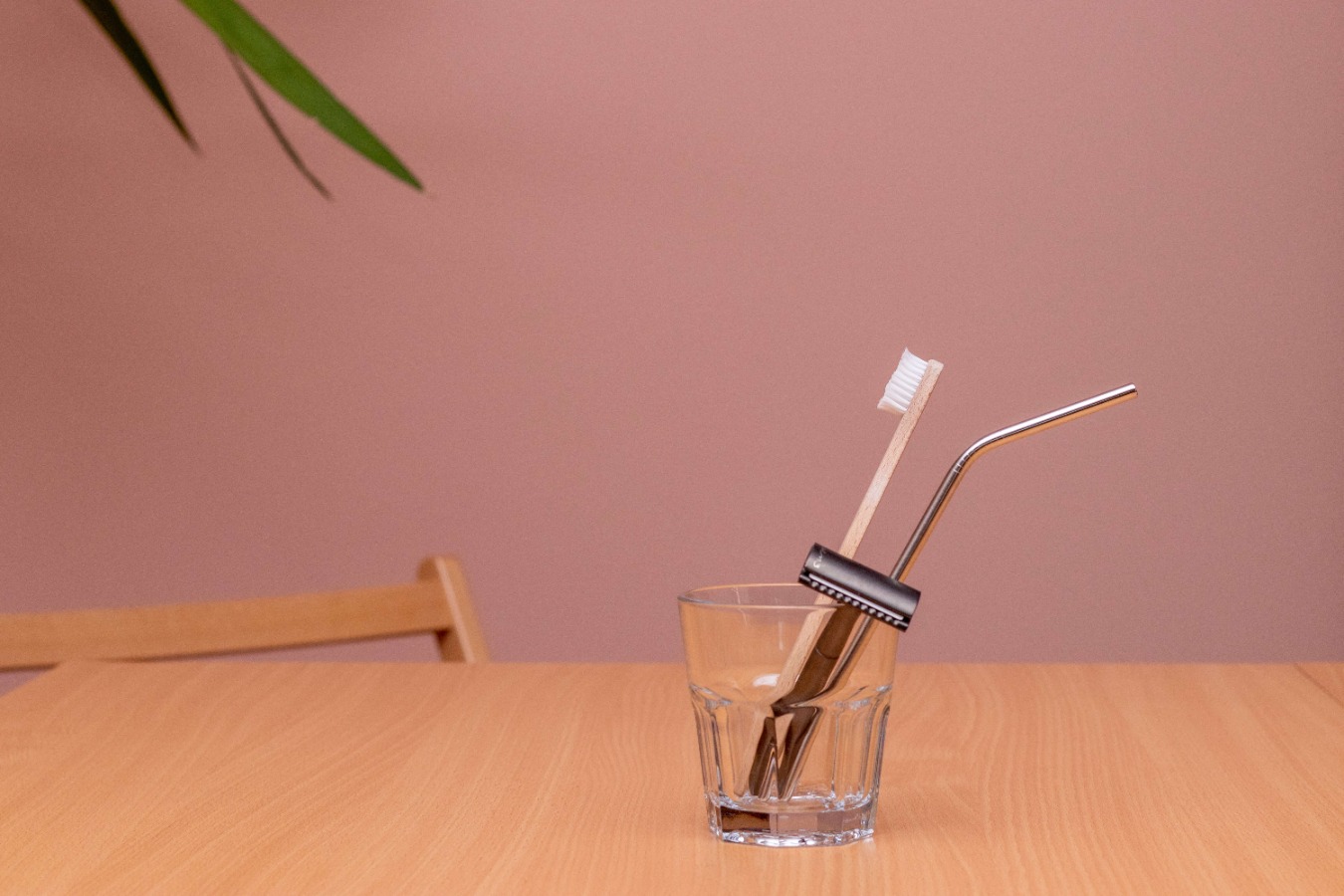 Bamboo toothbrush, safety razor and stainless steel straw in a glass