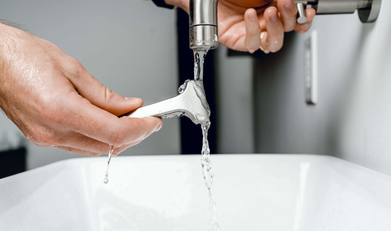 Supply razor being rinsed under water from faucet